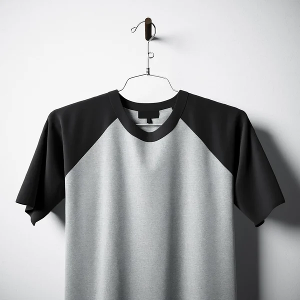 Closeup of blank cotton tshirt  gray and black colors hanging in center  empty concrete wall. Clear label mockup with highly detailed texture materials. Square. Front side view. 3D rendering. — Stock Photo, Image