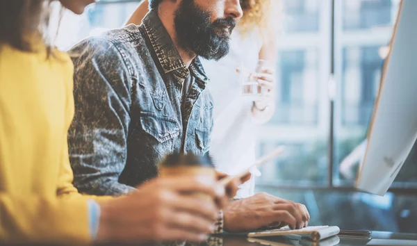 Homem barbudo digitando no teclado do desktop em um escritório. Jovens colegas de trabalho discutindo ideias de negócios no local de trabalho.Horizontal, turvo . — Fotografia de Stock