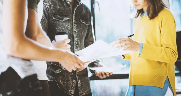 Man met de papieren in zijn handen en vrouw document te ondertekenen. Collega's team werken in zonnig kantoor in de buurt van het venster. Horizontale, onscherpe achtergrond. — Stockfoto