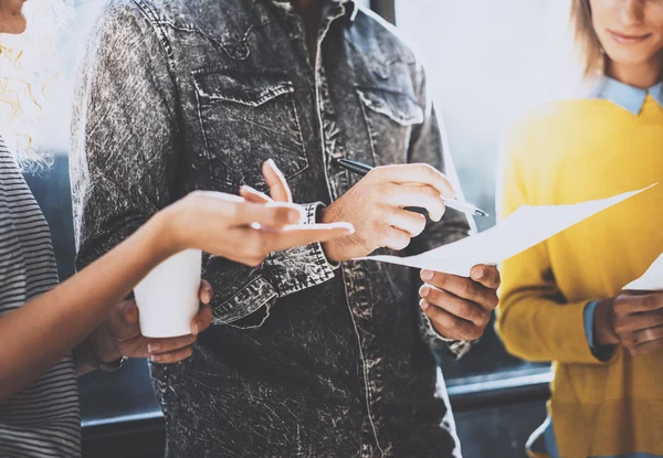 Ungt team av medarbetare att göra bra affärer diskussion i soliga kontor nära fönstret. Man håller ett papper i hans händer. Horisontell, suddig. — Stockfoto