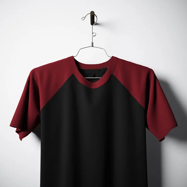 Closeup of blank cotton tshirt, black and red colors hanging in center empty concrete wall. Clear label mockup with highly detailed textured materials. Square. Front side view. 3D rendering. — Stock Photo, Image