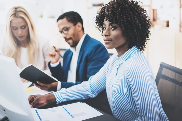 Groep van zakelijke partners werken samen aan online bankieren project in moderne kantoor. Jonge aantrekkelijke Afrikaanse vrouw die lacht op werkplek, teamwerk concept. Horizontale, onscherpe achtergrond. — Stockfoto