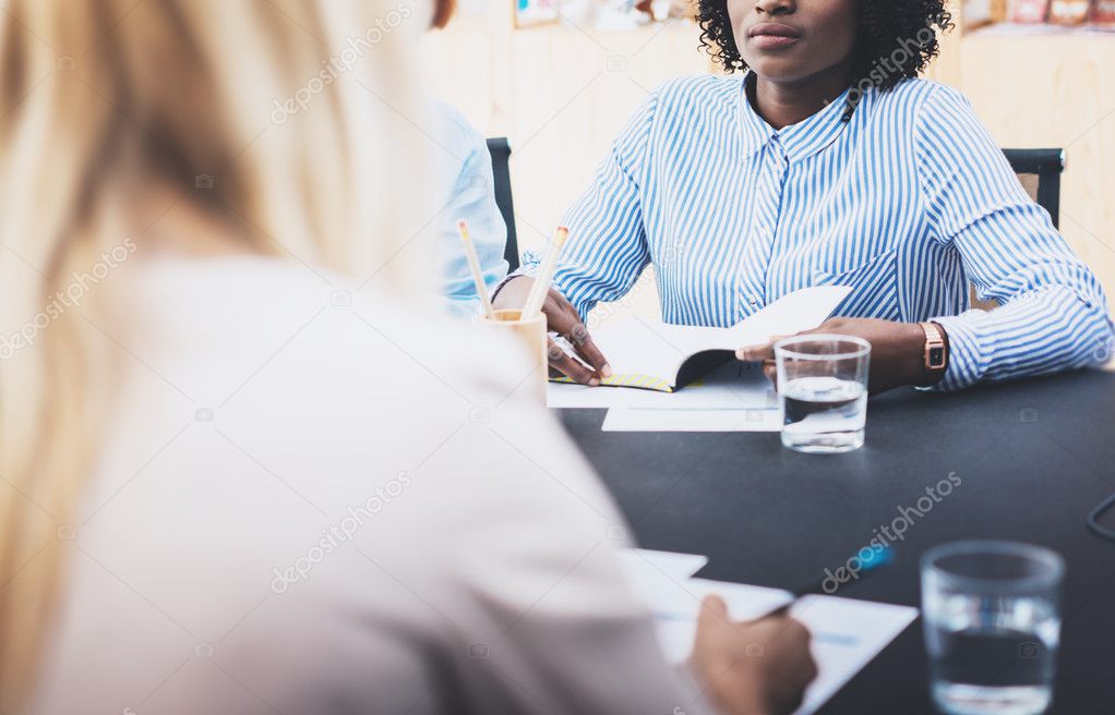 Closeup of beautiful womans making business meeting in modern office. Group girls coworkers discussing together new fashion project. Horizontal, blurred background.