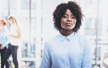Kameraya bakarak afro ile oldukça Afro-Amerikan iş kadını portresi. Coworking arka planda modern ofis takımda. Yatay, bulanık.