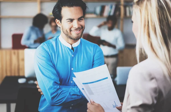 Zwei Mitarbeiter, die ein tolles Geschäftsgespräch in modernem Büro führen. Erfolgreicher selbstbewusster hispanischer Geschäftsmann im Gespräch mit einer jungen Frau. horizontaler, verschwommener Hintergrund. — Stockfoto