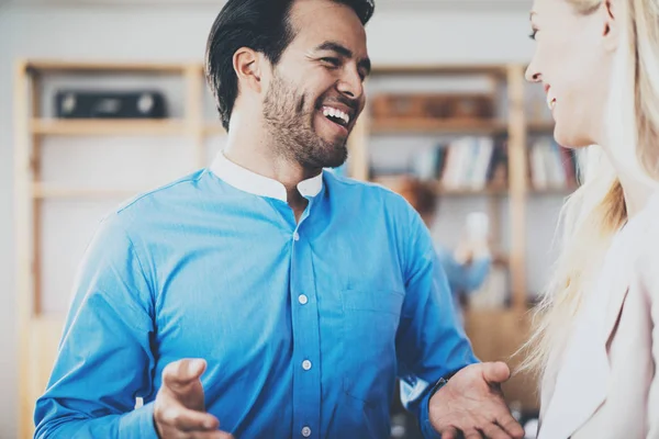 Twee jonge zakenpartner glimlachend na grote discussie in moderne kantoor. Horizontale, onscherpe achtergrond. — Stockfoto