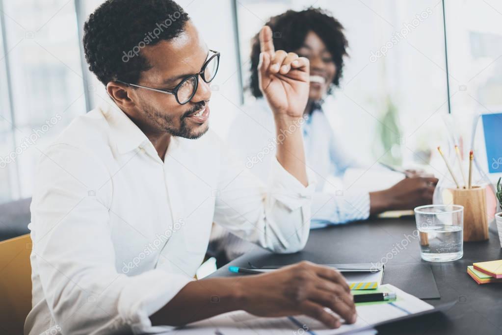 Black african project manager explaning business strategy in meeting room.Two young entrepreneurs working together in a modern office.Horizontal,blurred background.