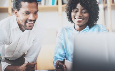 İki genç iş arkadaşlarınızla birlikte çalışma bir modern coworking studio. Dizüstü bilgisayar kullanarak ve yeni başlangıç projesi tartışmaya Afrika siyah iş ortakları. Yatay, bulanık.