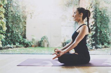 Pratik yoga kapalı güzel genç kadın portresi. Sınıf uygulama lotus bulunduğu güzel bir kız. Sakinlik ve sakin ol, mutluluk. Yatay, bulanık arka plan.