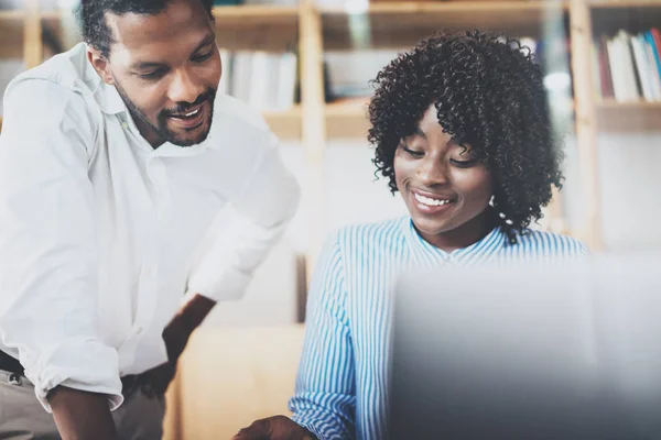 Gruppen av unga medarbetare arbetar tillsammans i ett modernt kontor. Afrikanska svart affärskollegor använder laptop och diskutera nya startup projekt. Horisontell, suddig. — Stockfoto