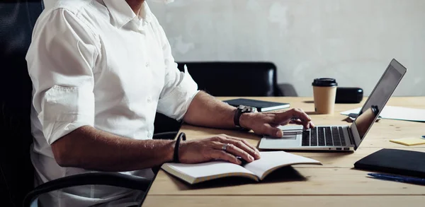 Erwachsene bärtige Geschäftsmann trägt eine klassische Brille und arbeitet am Holztisch in modernen loft.stylish Mann mittleren Alters mit Notizbuch. horizontal breiter, unscharfer Hintergrund. — Stockfoto