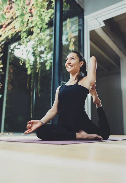 Retrato de una joven feliz practicando yoga en interiores. Hermosa chica práctica de relajación asana en clase.Tranquilidad y relax, concepto de felicidad femenina.Horizontal, fondo borroso . — Foto de Stock