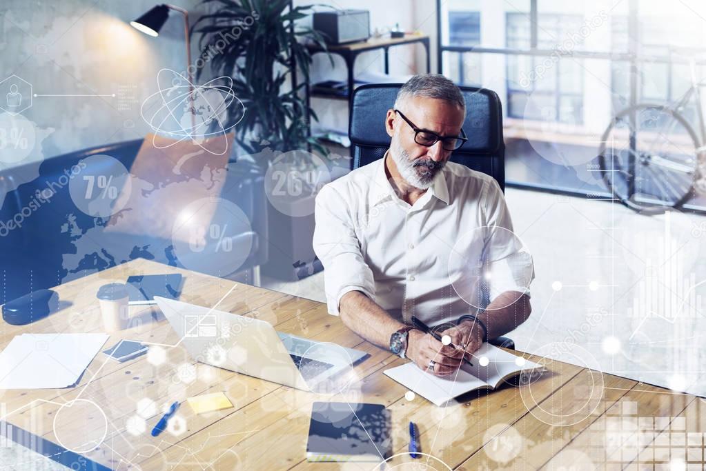 Concept of digital screen with virtual icon,diagram, graph interfaces.Adult successful businessman wearing a classic glasses and working at the wood table in modern coworking studio.Horizontal.