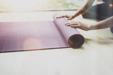Closeup görünümünü pratik yoga kapalı muhteşem bir genç kadın. Güzel kız paspaslar uygulama sınıfı için hazırlanıyor. Sakinlik ve sakin ol, mutluluk kavramı. Yatay, bulanık arka plan, fişekleri.