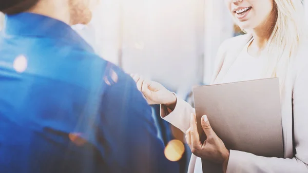 Two coworkers discussing business project in modern office.Successful confident hispanic businessman talking with blonde woman. Horizontal closeup, flare, blurred background. — Stock Photo, Image