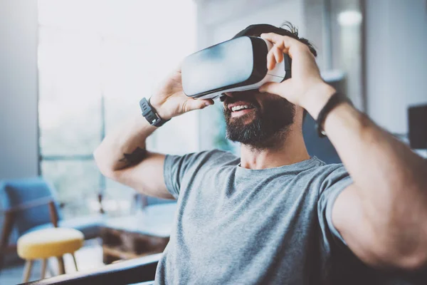 Skäggig man bär virtuell verklighet skyddsglasögon i moderna coworking studio. Smartphone med Vr-headset. Horisontell, suddig. — Stockfoto