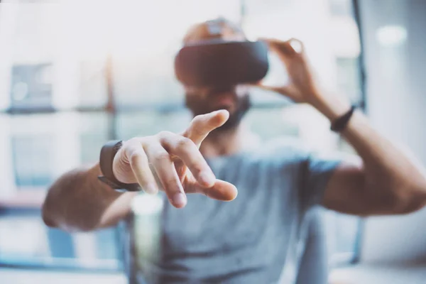 Närbild av manlig hand. Skäggig ung man klädd i virtuell verklighet skyddsglasögon i moderna coworking studio. Smartphone med Vr-headset i office. Horisontell, suddig. — Stockfoto