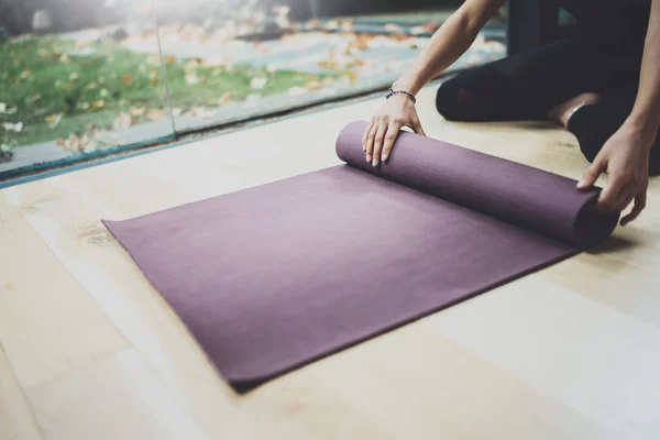 Gorgeous young woman practicing yoga indoor. Beautiful girl preparing material for practice class.Calmness and relax, female happiness concept.Horizontal, blurred background. — Stock Photo, Image