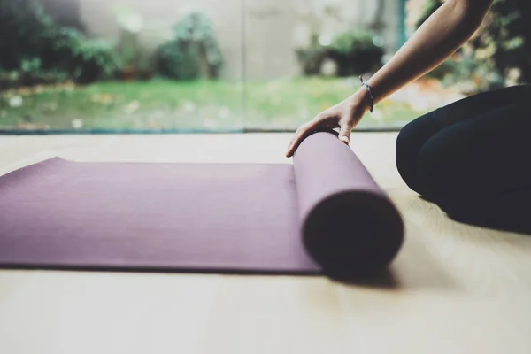 Vista de cerca de la hermosa joven que practica yoga en interiores. Hermosa chica preparando esteras para la práctica class.Calmness y relajarse, concepto de felicidad femenina.Horizontal, fondo borroso . —  Fotos de Stock