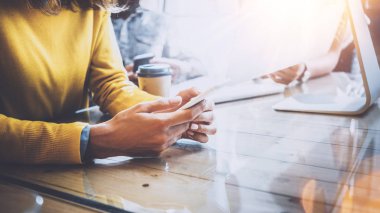 Ekip çalışması kavramı. İş arkadaşlarınızla birlikte modern coworking ofisinde çalışan genç takım. Eller akıllı telefon kullanan kadın. Adam iş üstünde okul sırası bilgisayar. Yatay, parlama efekti.