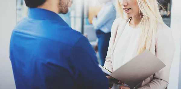 Two coworkers discussing startup project in modern coworking studio.Successful hispanic businessman talking with blonde woman. Horizontal closeup, blurred background. — Stock Photo, Image