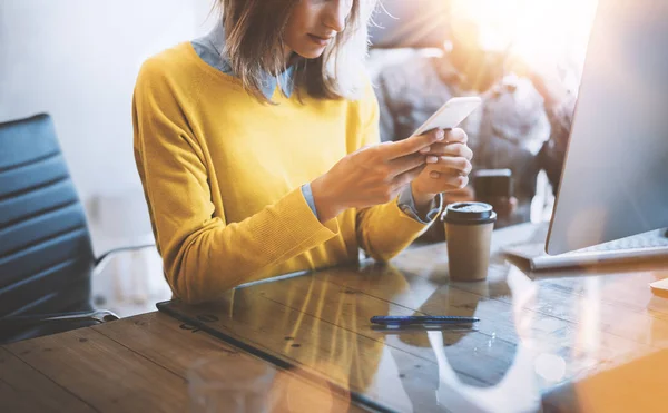 Genç takım birlikte modern coworking uzayda mobil cihazlar kullanarak iş. Güzel kız smartphone ileti gönderme. Yatay. Arka plan bulanık fişekleri etkisi. — Stok fotoğraf