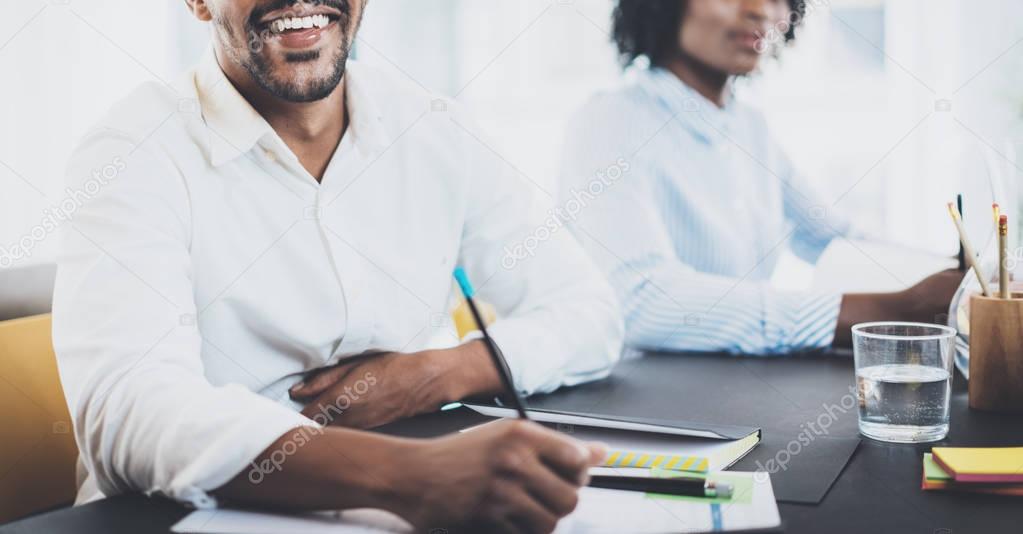 Black african businessman smiling in meeting room.Two young entrepreneurs working together in a modern office.Horizontal wide,blurred background.