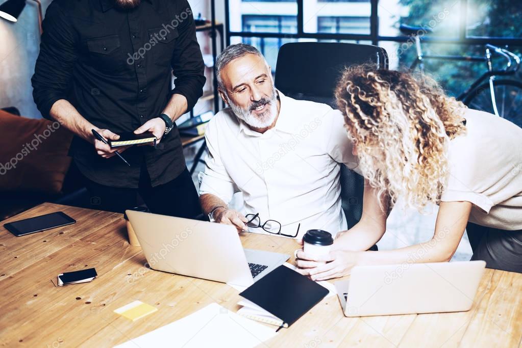 Young team of coworkers making great work discussion in modern office.Bearded man talking with marketing director and assistant manager.Business people meeting concept.Horizontal, blurred background.