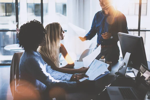 Junges Team von Coworkern, die großartige Besprechungen in modernen Coworking-Büros führen. Hispanischer Geschäftsmann im Gespräch mit zwei schönen Frauen. Teamarbeitsprozess. Horizontal, verschwommener Hintergrund, Sonneneffekt. — Stockfoto