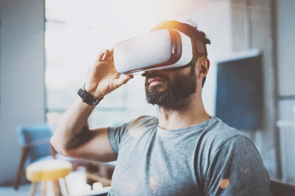 Skäggig man bär virtuell verklighet glasögon i modern inredning coworking studio. Smartphone med Vr glasögon headset. Horisontell, nödraketer effekt, suddig bakgrund. — Stockfoto