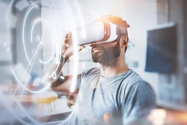 Concepto de pantalla digital, conexión e interfaces.Young beraded hipster disfrutando de gafas de realidad virtual en el estudio loft de diseño moderno. uso de teléfono móvil con gafas VR auriculares. Horizontal, llamarada, borrosa . —  Fotos de Stock