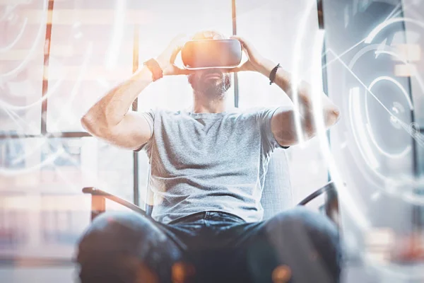 Concepto de pantalla digital, conexión e interfaces.Young beraded hipster disfrutando de gafas de realidad virtual en el estudio loft de diseño moderno. uso de teléfono móvil con gafas VR auriculares. . — Foto de Stock