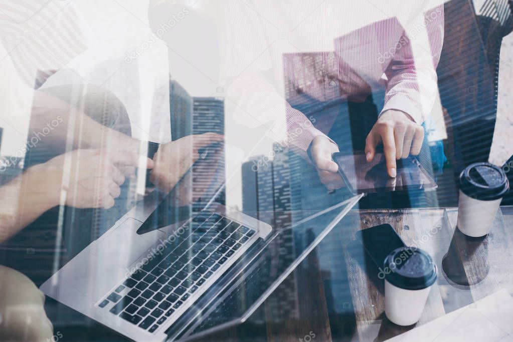 Closeup of young businessman working together on new startup project in modern office.Double exposure,business people using mobile devices.Skyscraper building at the blurred background.Horizontal.