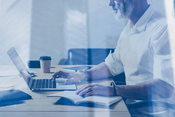 Doppia esposizione concept.Adulto uomo d'affari barbuto che lavora al tavolo in legno in luogo moderno.Attraente uomo di mezza età utilizzando notebook. . — Foto Stock