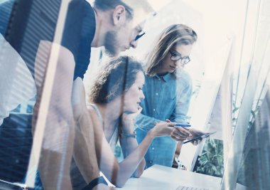 Çekici genç adam stüdyo coworking içinde iki kadının çalışma sakallı. Başarılı iş kavramı. Çift pozlama, gökdelen ofis binası üzerinde arka plan bulanık.