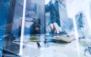 Ekran dijital tablet dokunmadan eller çift pozlama. Kavram iş adamları mobil araçları kullanma. Closeup görünümü modern gökdelen ofis binası üzerinde arka plan bulanık. Yatay, film etkisi.