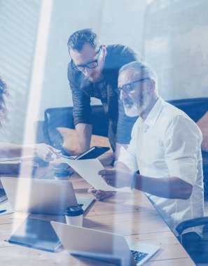 Çift pozlama kavramı. Genç takım iş ortakları büyük tartışma modern coworking studio, yapma. Meslektaşları ile strateji hakkında konuşan sakallı işadamı adam. Dikey, bulanık arka plan.
