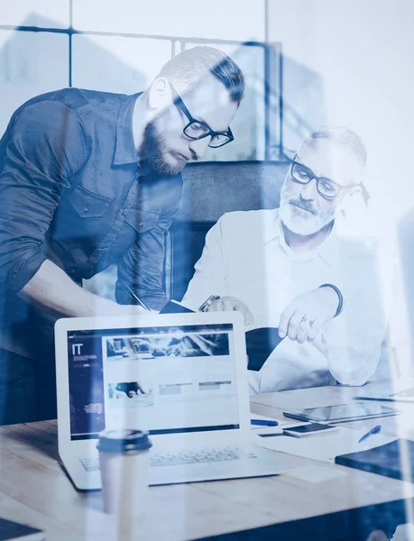 Double exposure concept.Team of business people making great work discussion in studio.Young bearded man showing statistic repot, using laptop.Skyscraper office building on blurred background.Vertical . — стоковое фото
