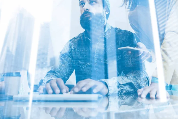 Double exposure concept.Bearded man working in the office.Coworker typing at a computer keyboard.Woman holding smartphone hand.Skyscraper  building blurred background.Horizontal. — Stock Photo, Image