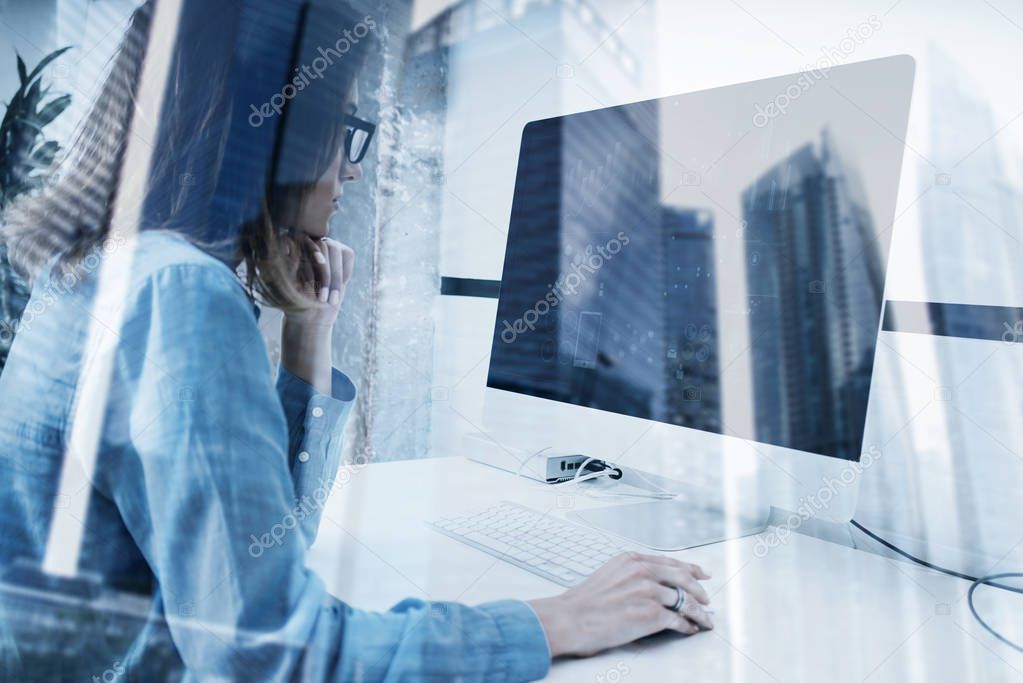 Young girl working on computer in modern coworking studio.Icons,graphs and diagramm monitor.Double exposure,skyscraper building, blurred background. Horizontal.