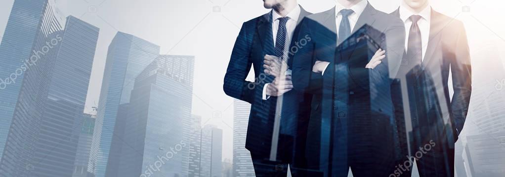 Group of three young businessman wearing suits and posing against backdrop the modern city.Concept successful business.Double exposure,skyscraper building at blurred background.Horizontal wide.