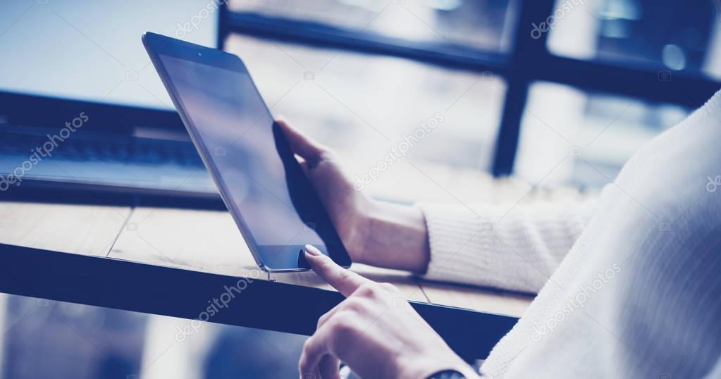 Closeup view of female hand touching button on black tablet at the wooden desk.Concept young business people using mobile devices.Horizontal, blurred background.Film effect.
