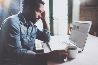 Güneşli sabah siyah kahve yudumlarken laptop financical haber okuma dalgın Afrika delikanlı. Evde çalışan insanlar coworking kavramı. Arka plan bulanık, işaret fişeği.