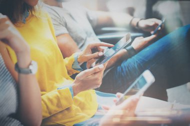 Tr elele ve dijital tablet, smartphone kullanarak koltukta oturan genç hipsters grubudur. Coworking takım kavramı. Yatay, bulanık arka plan.
