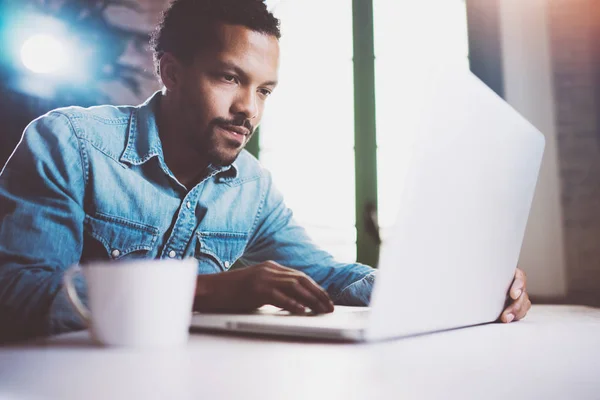 Pensive bearded African man working on laptop while spending time at home. Concept of young business people using mobile devices.Blurred background, crop — стоковое фото