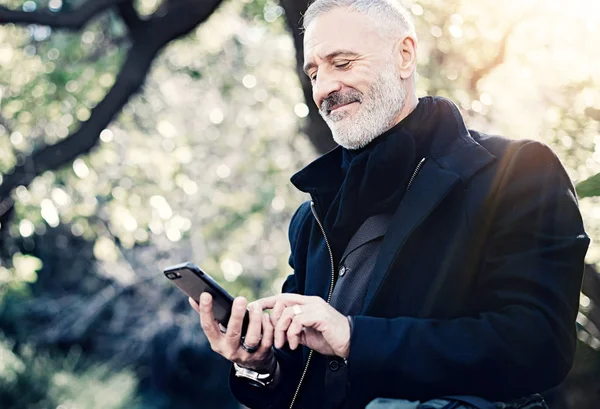 Primer plano retrato de feliz adulto atractivo hombre de negocios mensaje de texto en el teléfono inteligente, mientras que pasar tiempo en el parque de la ciudad en el día soleado.Horizontal, fondo borroso . — Foto de Stock