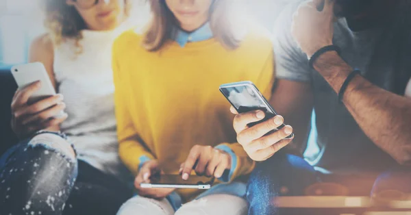 Groep van jonge hipsters zittend op de Bank nl handen te houden en het gebruik van elektronische gadgets. Naaiatelier teamwerk concept. Horizontale, onscherpe achtergrond. — Stockfoto