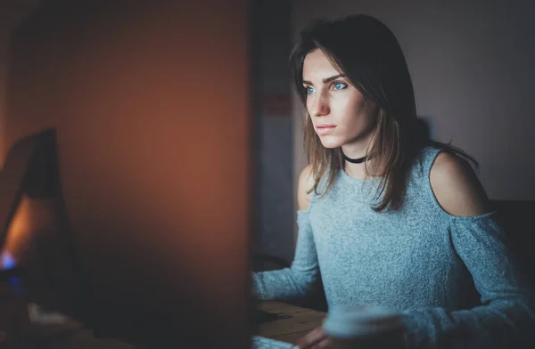 Junge schöne Frau, die nachts im modernen Loft-Büro arbeitet. Mädchen mit modernen Desktop-Computer, verschwommener Hintergrund. horizontal, Filmeffekt. — Stockfoto