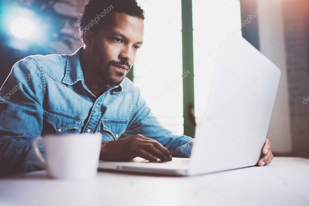 Pensive bearded African man working on laptop while spending time at home.Concept of young business people using mobile devices.Blurred background, crop