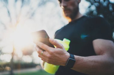 Kontrol kas sakallı atlet iyi egzersiz açık oturum sonra smartphone başvurusunda Şehir Parkı üzerinde kalori yaktı. Arka plan bulanık.